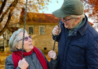Habitat inclusif : Deux personnes âgées discutent dans un jardin devant une maison.