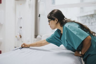 Une infirmière en train de faire un lit d'hôpital